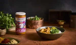 Słoik sosu Tikka Masala i miska z daniem z ryżem, kurczakiem i kolendrą.