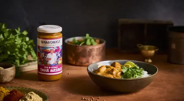 Słoik sosu Tikka Masala i miska z daniem z ryżem, kurczakiem i kolendrą.