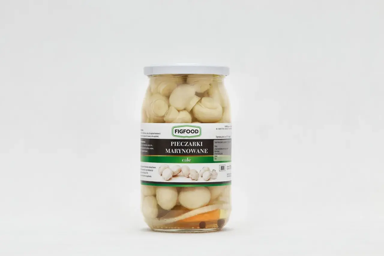 Słoik z marynowanymi pieczarkami marki Figfood, z widocznymi kawałkami warzyw i przypraw.